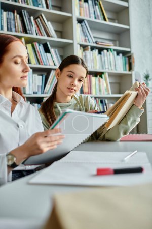 Una tutora pelirroja guía a una adolescente en una clase extraescolar en una mesa de la biblioteca, compartiendo conocimientos con la ayuda de una computadora portátil.