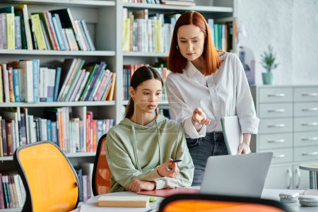Dos mujeres, un tutor y un estudiante, que participan en las lecciones extraescolares en una biblioteca, utilizando un ordenador portátil para la educación moderna.