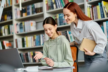 Photo for A tutor and a student, engage in after-school lessons in the library, focusing on a laptop for digital learning. - Royalty Free Image