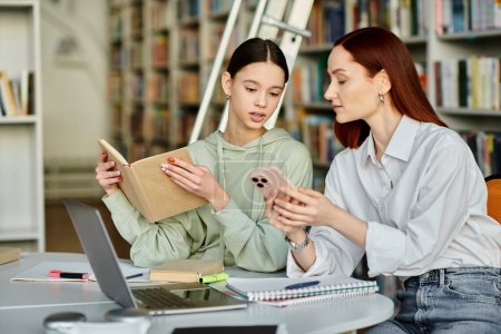 Un joven tutor con el pelo rojo enseña a una adolescente en una mesa de la biblioteca, utilizando un ordenador portátil para lecciones después de la escuela.