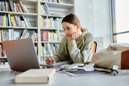 Adoleszenz versinkt im Laptop, während die Schularbeiten in einer heiteren Bibliothek abgeschlossen werden.