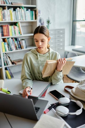 Una adolescente se sienta en un escritorio con una computadora portátil y libros, centrada en su tarea después de la escuela.