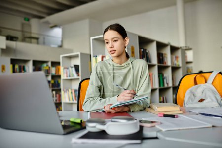 Ein Mädchen im Teenageralter vertieft in ihr Studium, tippt auf einem Laptop, während sie an einem Schreibtisch in einer ruhigen Bibliothek sitzt.