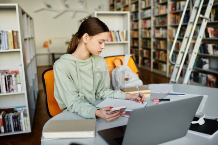 Une adolescente se concentre sur son ordinateur portable à une table dans une bibliothèque, s'engageant dans l'éducation moderne après l'école.