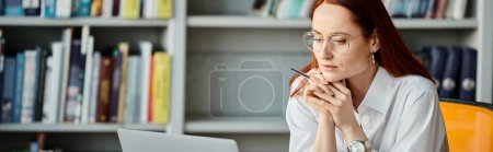 Téléchargez les photos : Une tutrice rousse enseigne avec diligence en ligne à l'aide d'un ordinateur portable pendant une leçon après l'école. - en image libre de droit