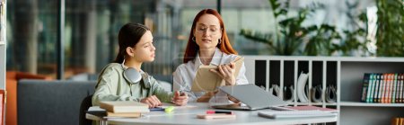 Redheaded woman tutors her teenage daughter, both focused on a laptop during after-school lessons in a modern office setting.