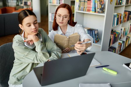 Un tutor, una mujer pelirroja, enseña a una adolescente después de la escuela, utilizando un ordenador portátil para facilitar el proceso de aprendizaje.