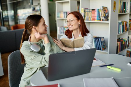 Una tutora, una pelirroja, enseña a una adolescente durante una lección extraescolar, ambas dedicadas a aprender juntas usando una computadora portátil.