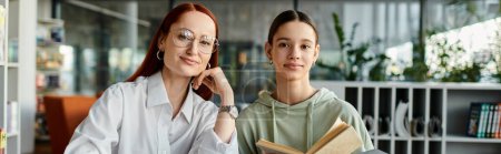 Téléchargez les photos : Redhead woman tutors teenage girl in library, both engrossed in book - en image libre de droit
