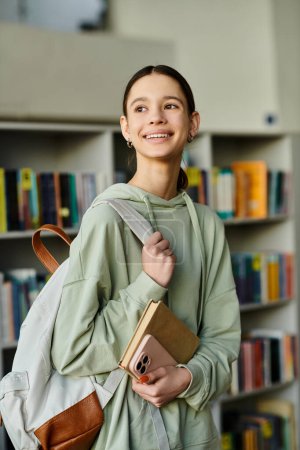 Téléchargez les photos : A teenage girl with a backpack full of books explores the library, eager to learn - en image libre de droit