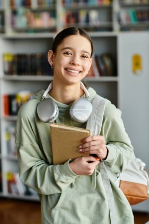 Una adolescente escucha un audiolibro con auriculares mientras sostiene un libro en un entorno de biblioteca.