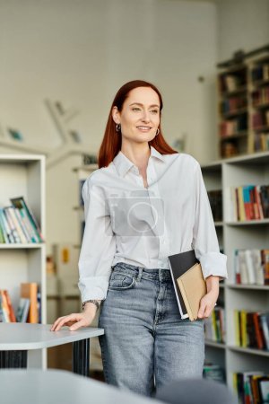 Redhead woman in a library, holding folder and smiling