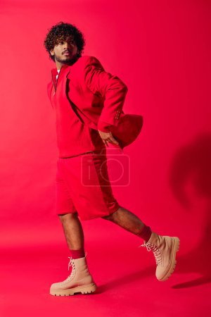 Foto de Hombre indio guapo con capucha roja posando sobre un vibrante telón de fondo. - Imagen libre de derechos