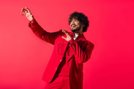 Photo for Handsome young Indian man in a red suit and white shirt posing on a vivid backdrop. - Royalty Free Image