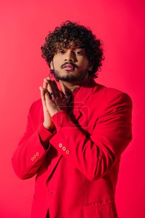 Téléchargez les photos : Un jeune indien habile pose dans un costume rouge vif sur un fond rouge vif. - en image libre de droit