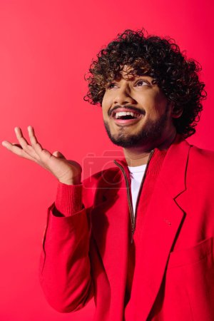 Photo for Handsome young Indian man strikes a comical pose in a vibrant red jacket. - Royalty Free Image