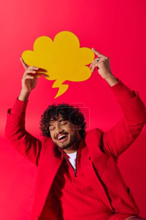 Handsome Indian man in colorful outfit holding speech bubble overhead.