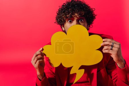 Téléchargez les photos : Un homme tenant une bulle de discours sur son visage, mettant en valeur le mystère et la communication. - en image libre de droit