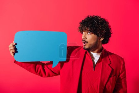 Handsome man in red jacket confidently presents blue speech bubble.