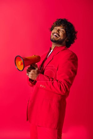 Hombre indio guapo en traje rojo con megáfono rojo y amarillo.