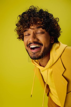 Téléchargez les photos : Handsome young Indian man with curly hair posing in a vibrant yellow jacket. - en image libre de droit