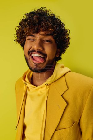 Schöner junger indischer Mann mit lockigem Haar posiert in einer leuchtend gelben Jacke.