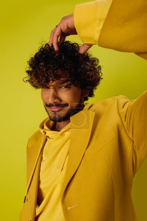 Photo for Handsome man with curly hair in vibrant yellow suit posing confidently. - Royalty Free Image