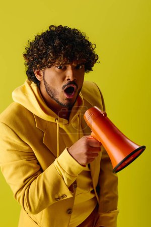 Man in yellow hoodie holds red and orange megaphone.