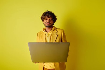 Photo for Handsome Indian man in yellow suit poses with laptop. - Royalty Free Image