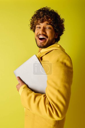 Photo for Handsome man with curly hair holding a laptop. - Royalty Free Image