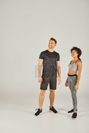 Foto de Una joven pareja deportiva interracial en activo posa confiadamente frente a un fondo limpio y blanco. - Imagen libre de derechos