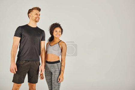 Foto de Un hombre y una mujer, ambos en ropa activa, de pie lado a lado contra un fondo gris en un entorno de estudio. - Imagen libre de derechos