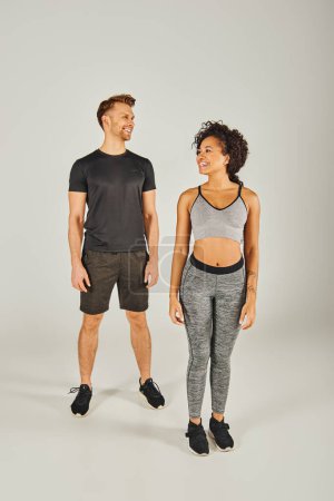 Téléchargez les photos : Jeune couple de sport interracial en tenue active debout en toute confiance devant un fond blanc. - en image libre de droit