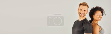 Téléchargez les photos : Jeune couple sportif interracial en tenue active posant devant un fond gris dans un décor de studio. - en image libre de droit