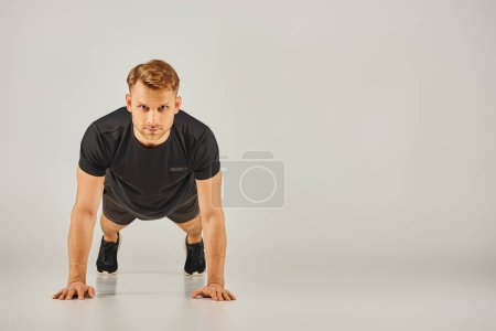 Ein junger, athletischer Mann in aktiver Kleidung, der Liegestütze auf weißem Hintergrund macht und Stärke und Fitness demonstriert.