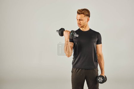 Photo for A young sportsman in active wear lifting dumbbells in a studio with a white background. - Royalty Free Image