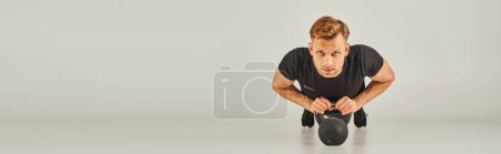 Photo for A man in a black shirt gracefully performing a squat on a white background in a studio, showcasing strength and flexibility. - Royalty Free Image