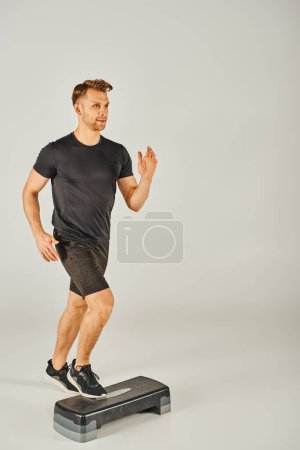 A young sportsman in active wear energetically running on a stepper in a studio against a white background.