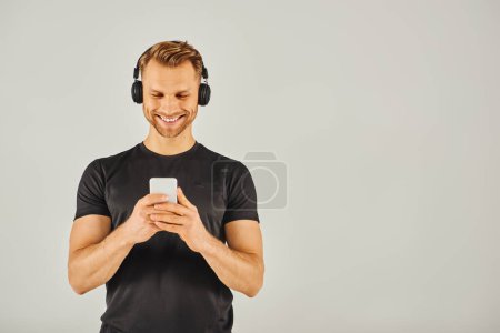 Téléchargez les photos : A young man in headphones gazes at his phone screen, absorbed in his digital world. - en image libre de droit