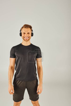 A young sportsman in active wear is engrossed in music, wearing headphones and a t-shirt, immersed in his workout routine.