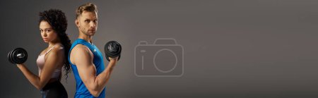 Téléchargez les photos : Couple multiculturel en tenue de sport tenant des haltères devant un fond gris dans un studio. - en image libre de droit
