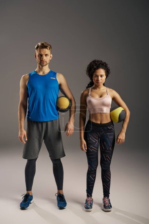 Young multicultural couple in active wear posing confidently for the camera in a studio setting.