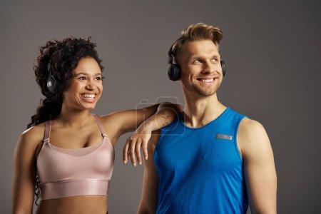 Photo for A young multicultural and fit couple, dressed in active wear, are striking a pose for a photo while wearing headphones. - Royalty Free Image
