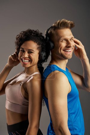 Foto de Una joven pareja multicultural en uso activo sonriendo mientras usa auriculares. - Imagen libre de derechos