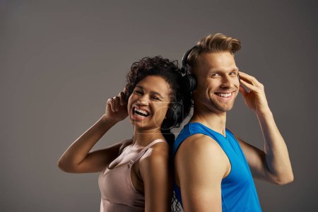 Téléchargez les photos : A young man and woman in activewear are immersed in music, listening through headphones with expressions of joy and connection. - en image libre de droit