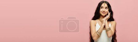 Téléchargez les photos : A captivating indian woman with long hair poses gracefully against a vibrant pink backdrop. - en image libre de droit