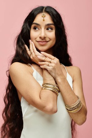 indian woman with long hair striking a pose on a pink background.