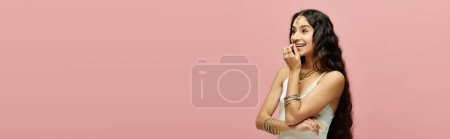 Téléchargez les photos : Femme indienne souriante aux cheveux longs devant fond rose. - en image libre de droit