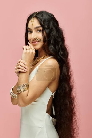 Téléchargez les photos : Une belle femme indienne aux cheveux longs frappant une pose sur un fond rose vif. - en image libre de droit