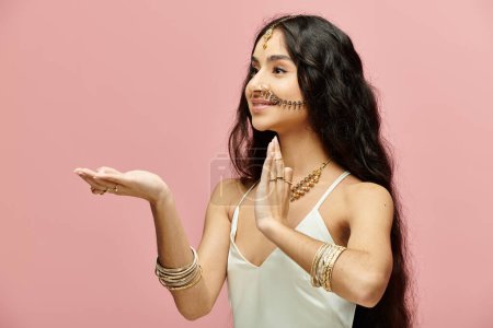 A indian woman with long hair is elegantly posing with her hands.